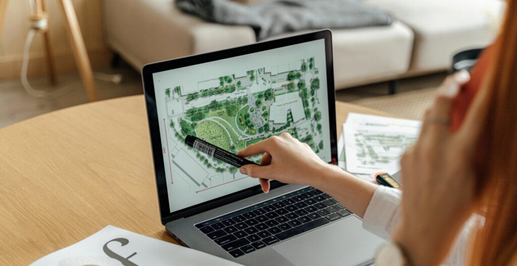 Architect reviewing landscape design on laptop, enhancing architectural projects from home office.